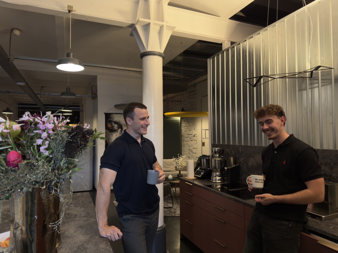 Zwei Mitarbeiter mit Kaffeetassen in der Büroküche